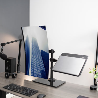 Freestanding monitor and laptop stand with elegant glass base for dual screen viewing and ergonomic placement.
